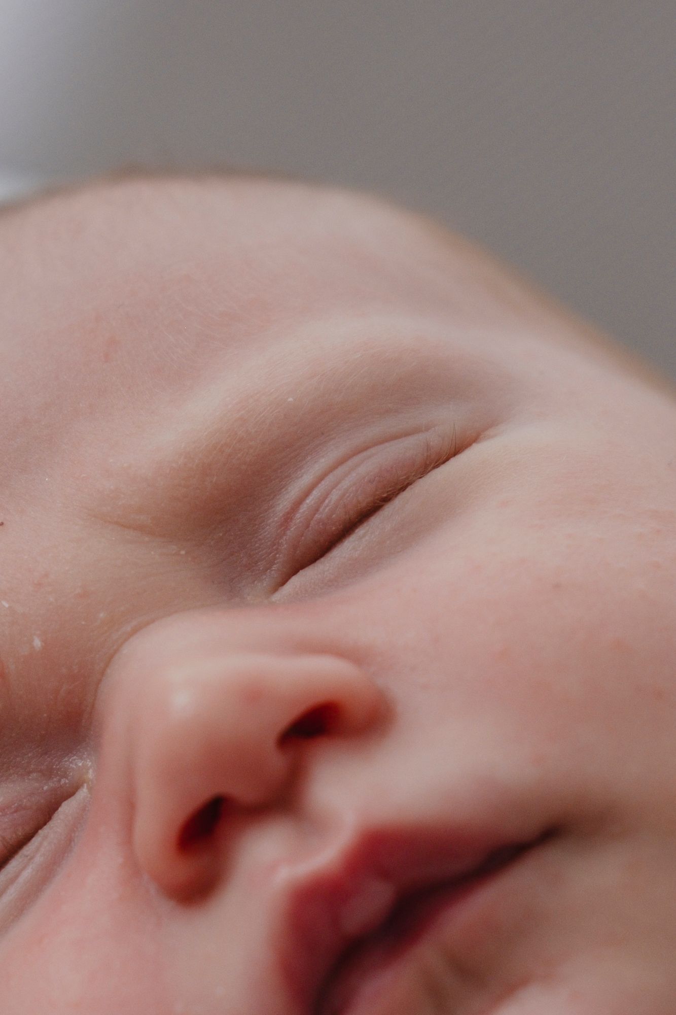 Extreme close-up macro shot of a peaceful sleeping newborn baby's face and features.