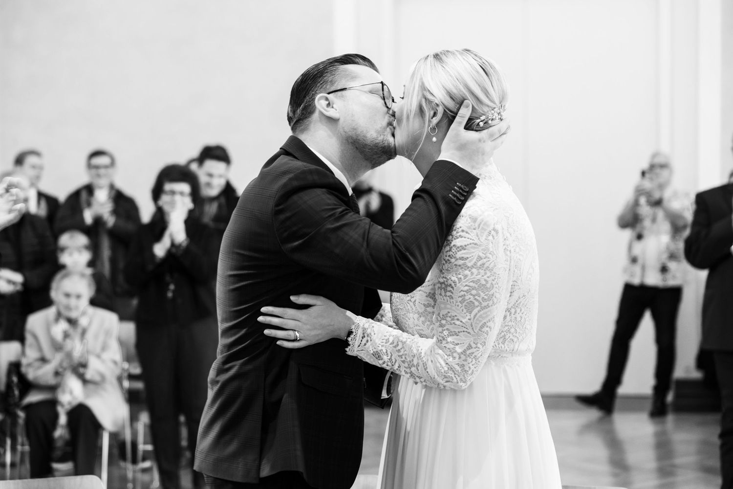 Bride and groom sharing first kiss at wedding ceremony in black and white.