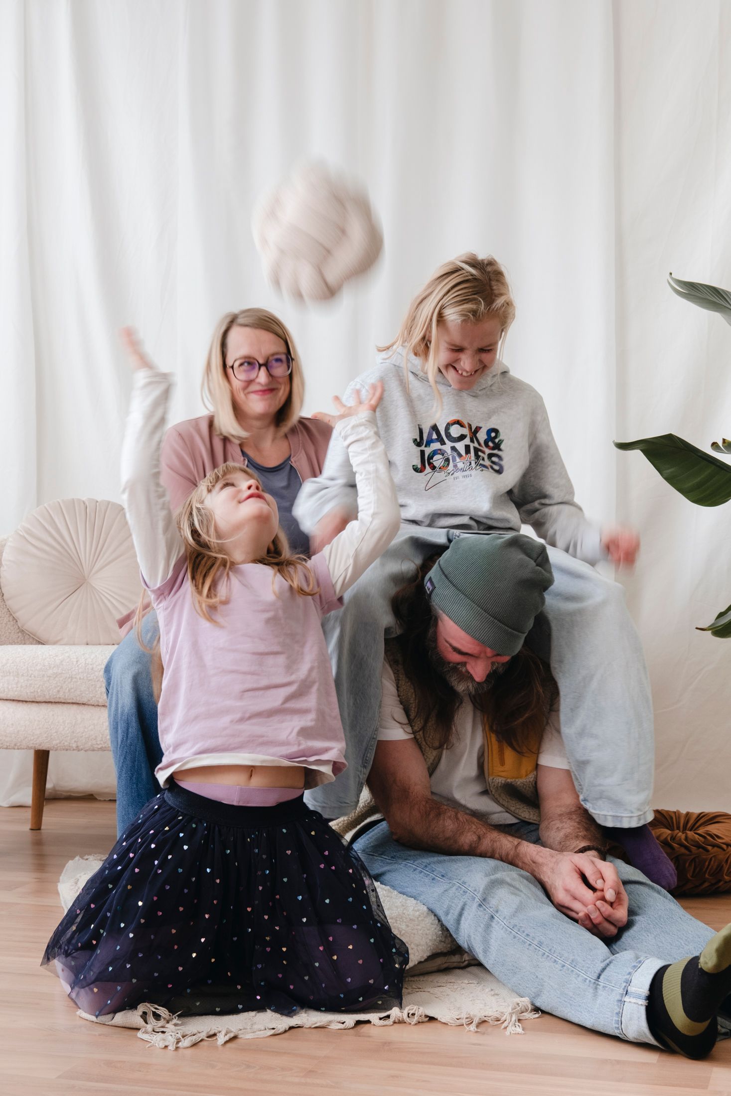 Joyful family of four playing and laughing together in living room.