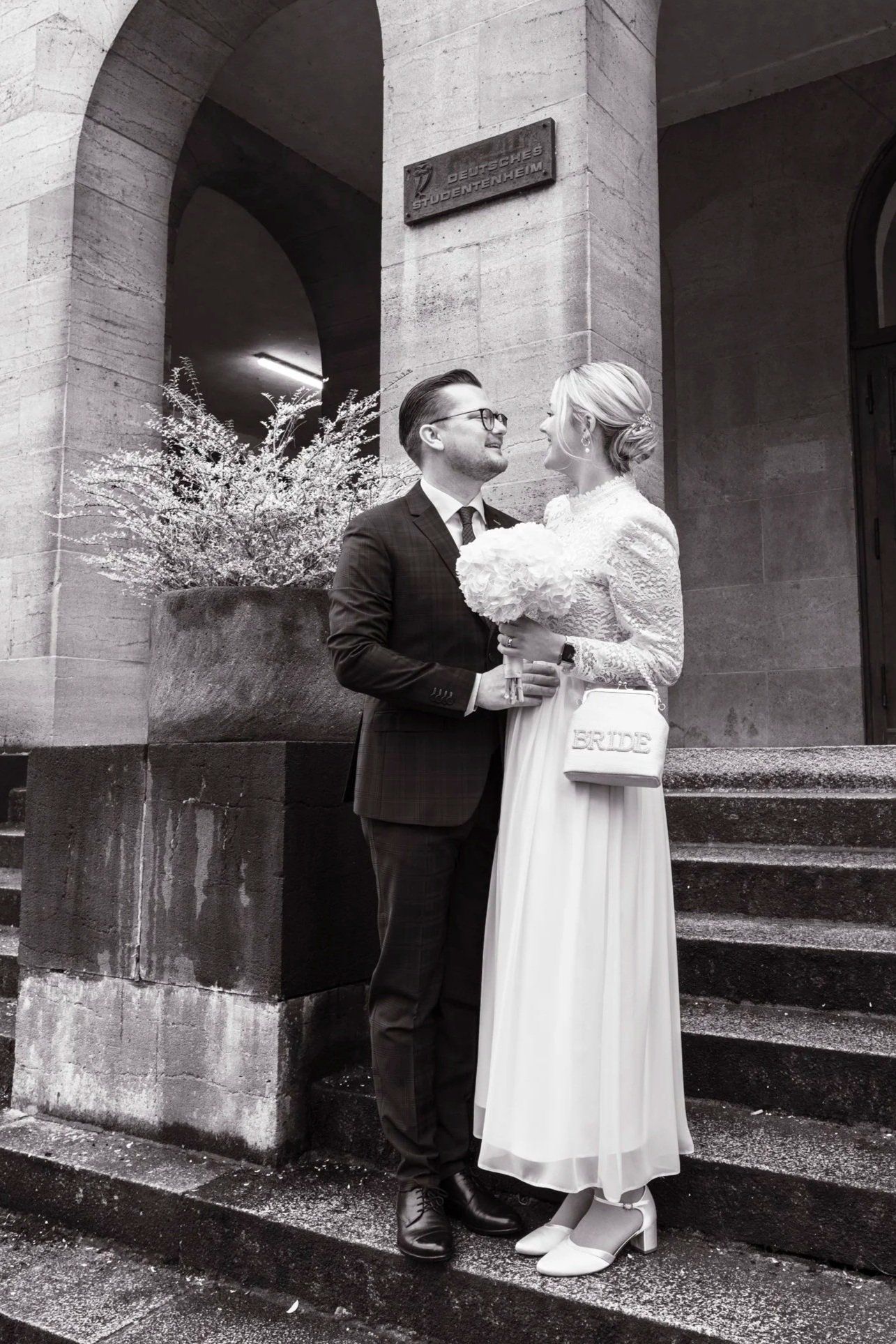 Elegant black and white portrait of newlyweds gazing at each other on stone steps.