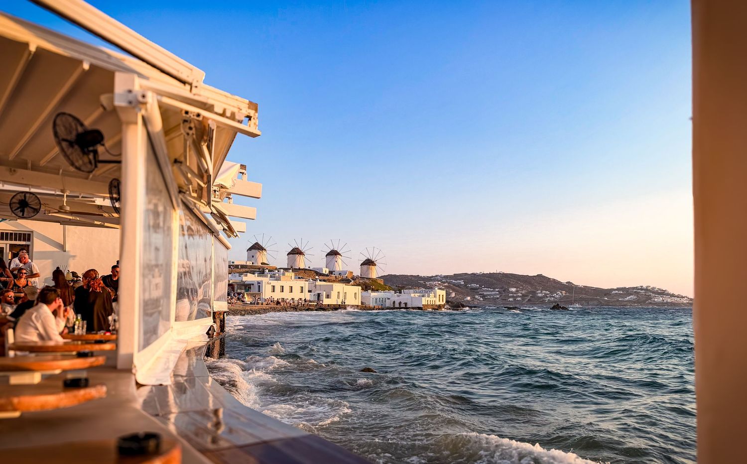 Waterfront restaurant overlooking windmills and the Aegean Sea in Mykonos Town, Greece