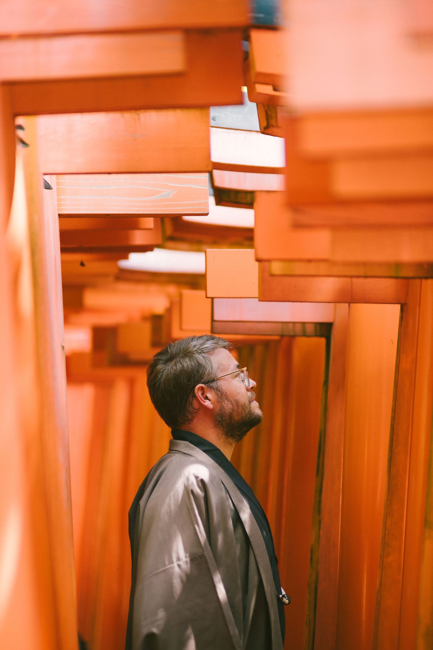 Tim standing beneath the red torii gates at Fushimi Inari Shrine in Kyoto, Japan