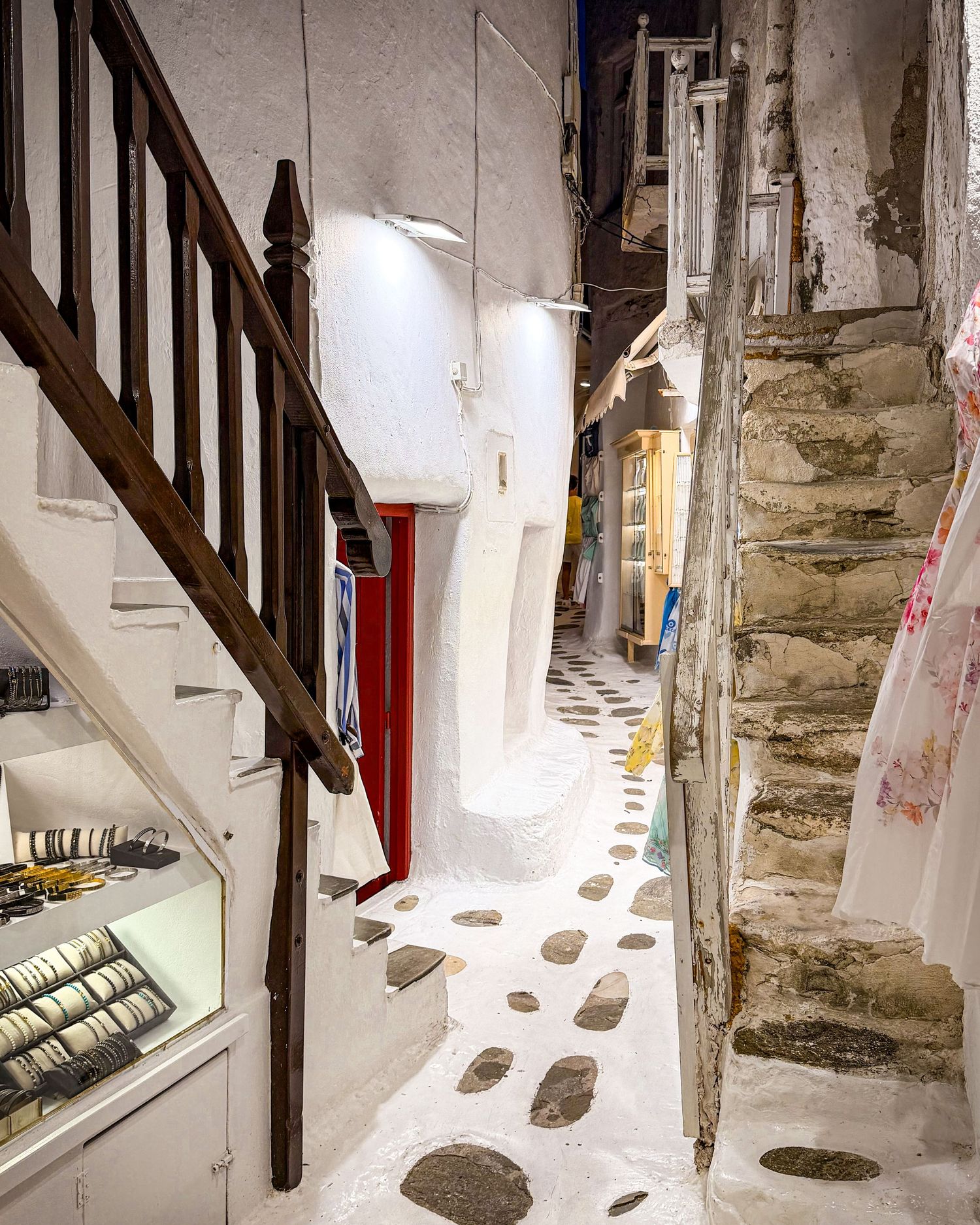 Narrow stone-paved alley winding between whitewashed buildings in Mykonos Town, Greece