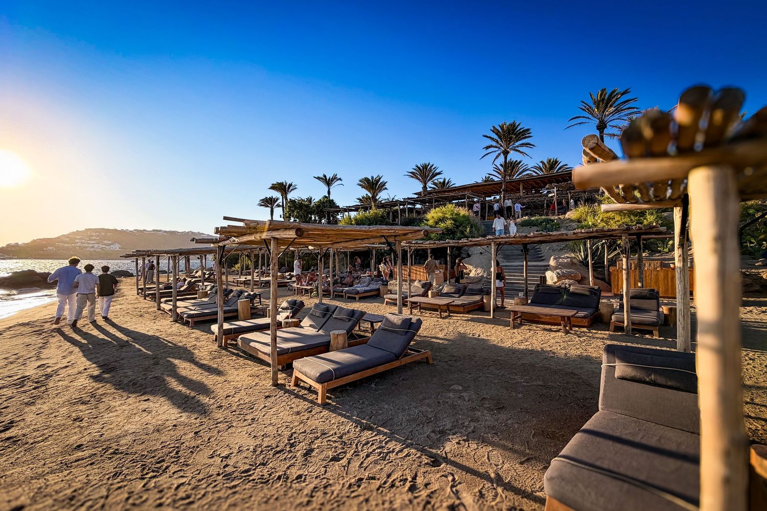 Beach cabanas overlooking the Aegean Sea at golden hour at Scorpios Beach in Mykonos, Greece