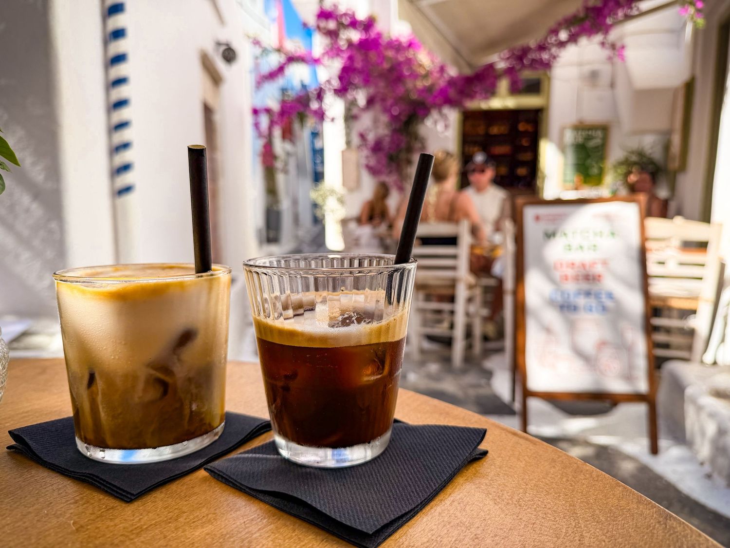 Cappuccino and freddo espresso at Mykonos Brunch Club overlooking a whitewashed street in Mykonos Town, Greece