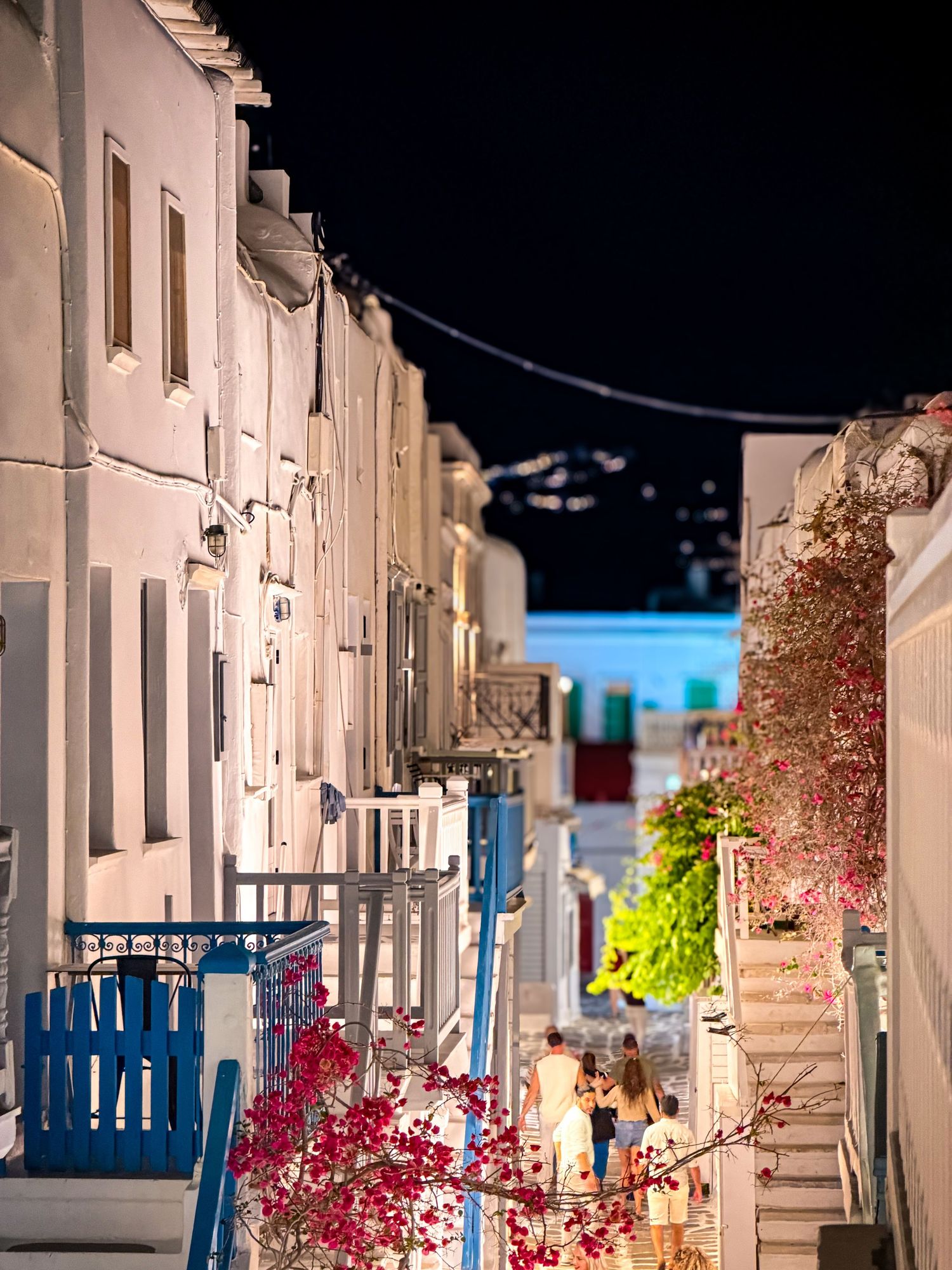 Narrow whitewashed street illuminated at night in Mykonos Town, Greece