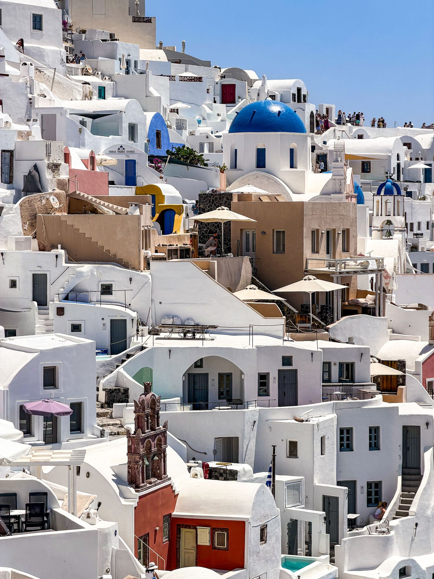 Whitewashed buildings along the caldera and blue-domed churches in Oia, Santorini, Greece