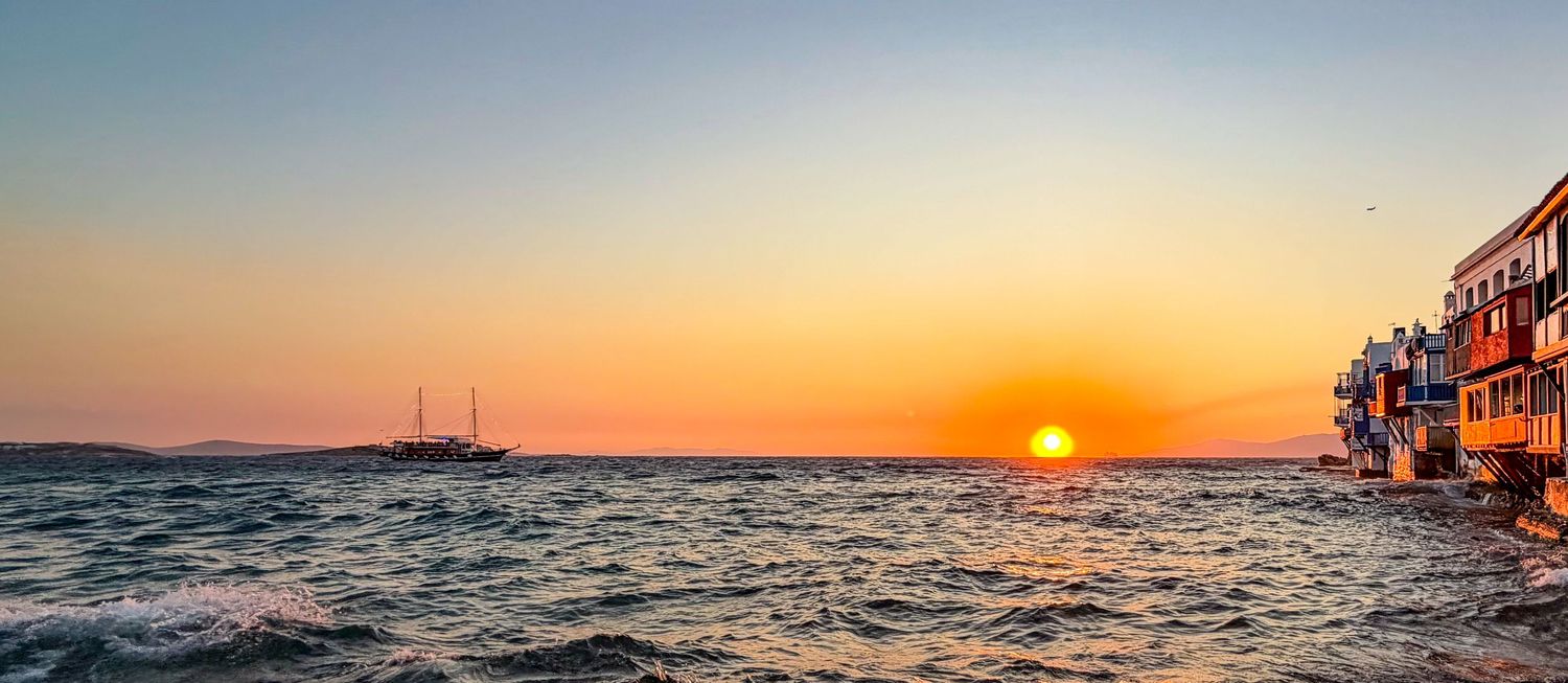 Boat on the Aegean Sea at sunset in Mykonos, Greece