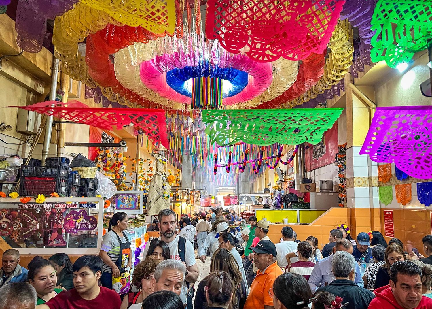Crowd walking through the smoky food alley at Mercado 20 de Noviembre during Día de Muertos in Oaxaca, Mexico