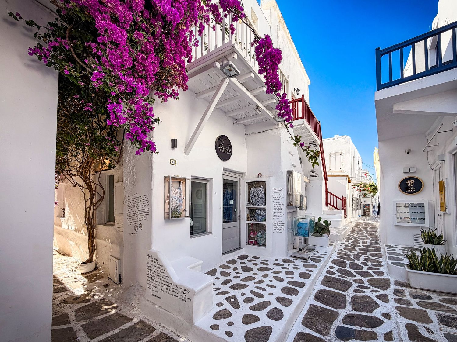 Whitewashed shops along a bougainvillea-lined street in Mykonos Town, Greece