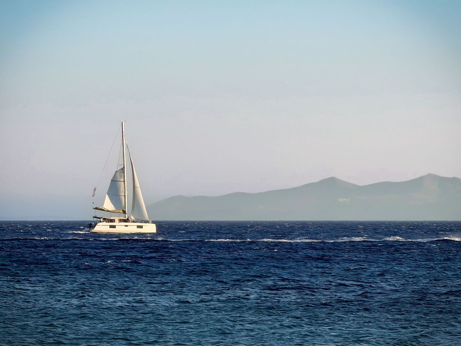 Sailboat crossing the Aegean Sea off the coast of Scorpios Beach in Mykonos, Greece