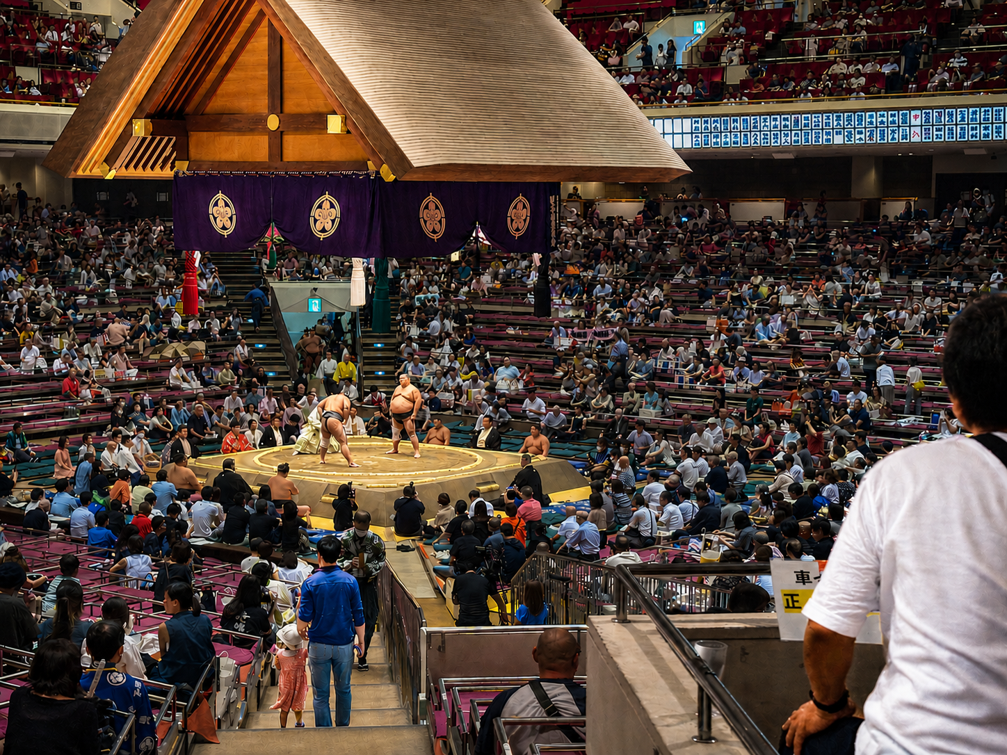 Boy holding his father's hand during a sumo wrestling tournament at Ryōgoku Kokugikan in Tokyo, Japan