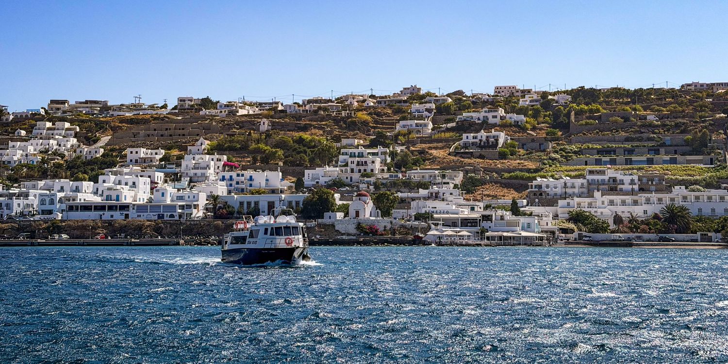 SeaBus in Mykonos Old Port with whitewashed buildings rising along the hillside in Mykonos, Greece