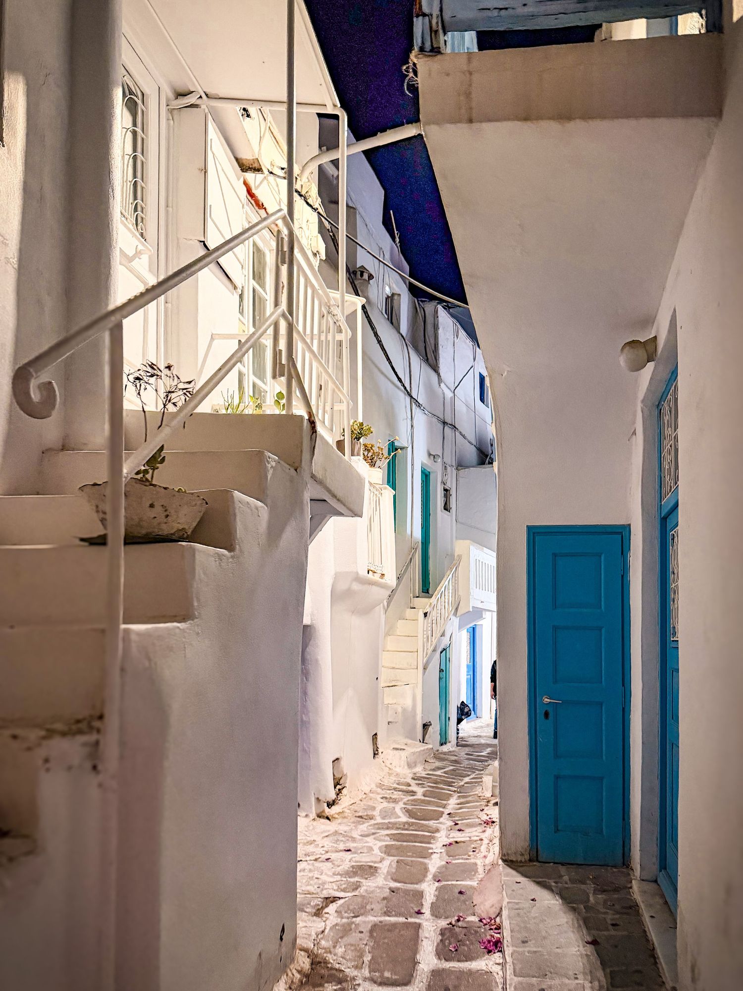 Narrow whitewashed alley with a blue door in Mykonos Town, Greece
