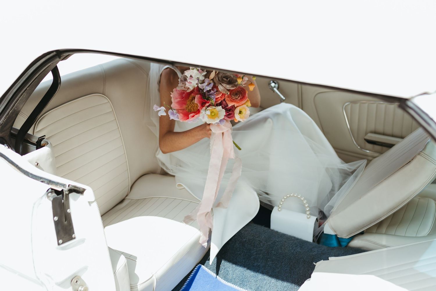 Bride with colourful pink flowers in her wedding car before her Liverpool wedding