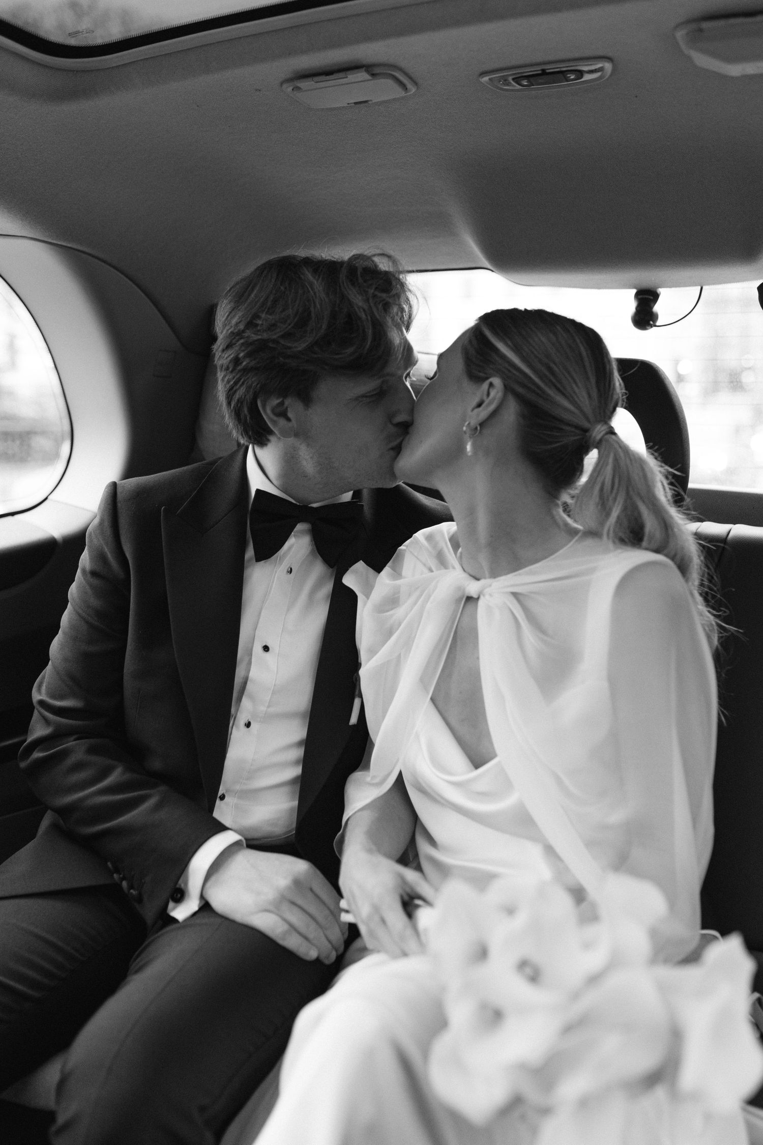 Bride and groom share a kiss in a London taxi at their wedding after Marylebone Town Hall wedding ceremony.