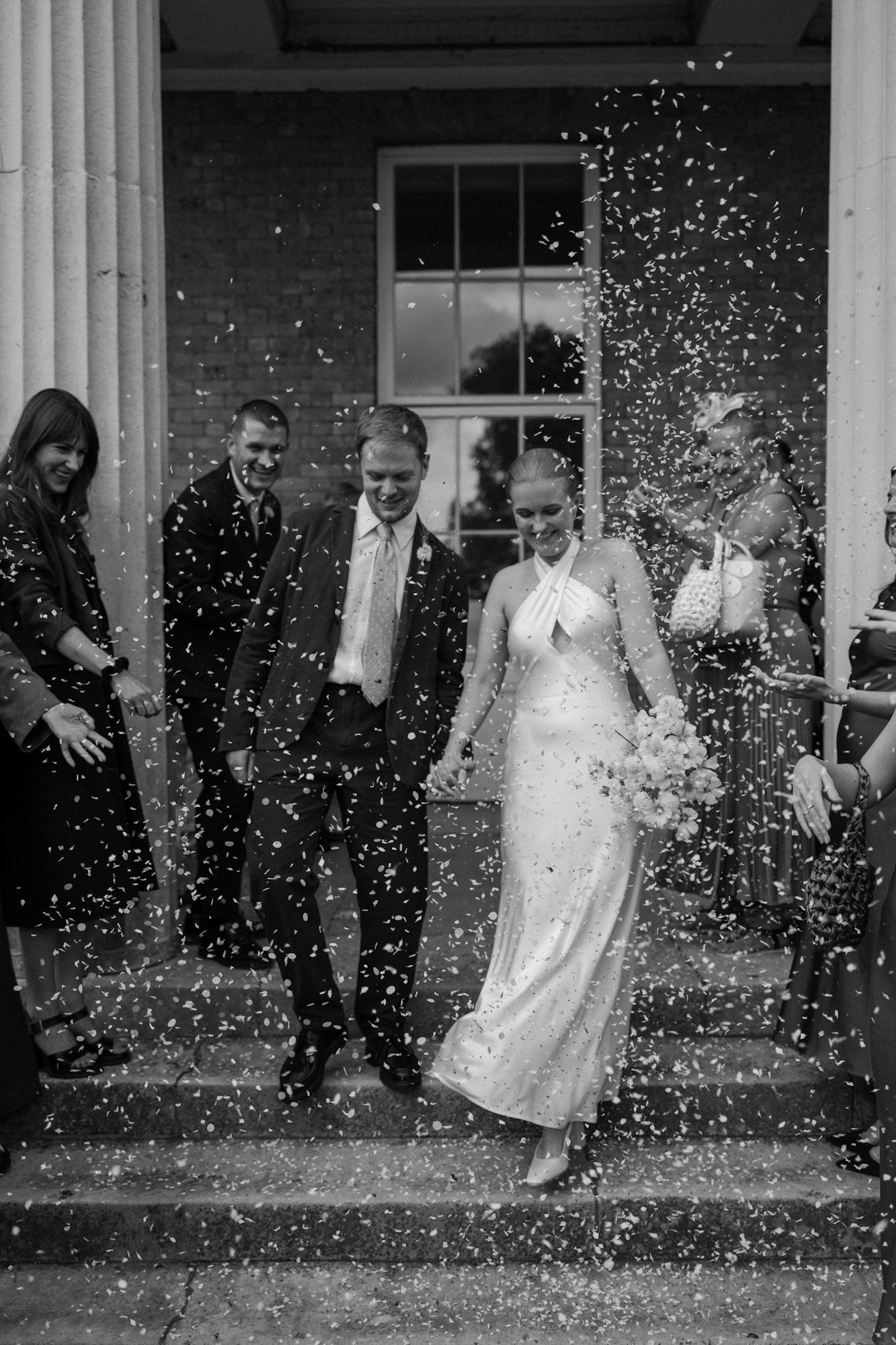 Bride and groom walk through confetti at their London Clissold House wedding.