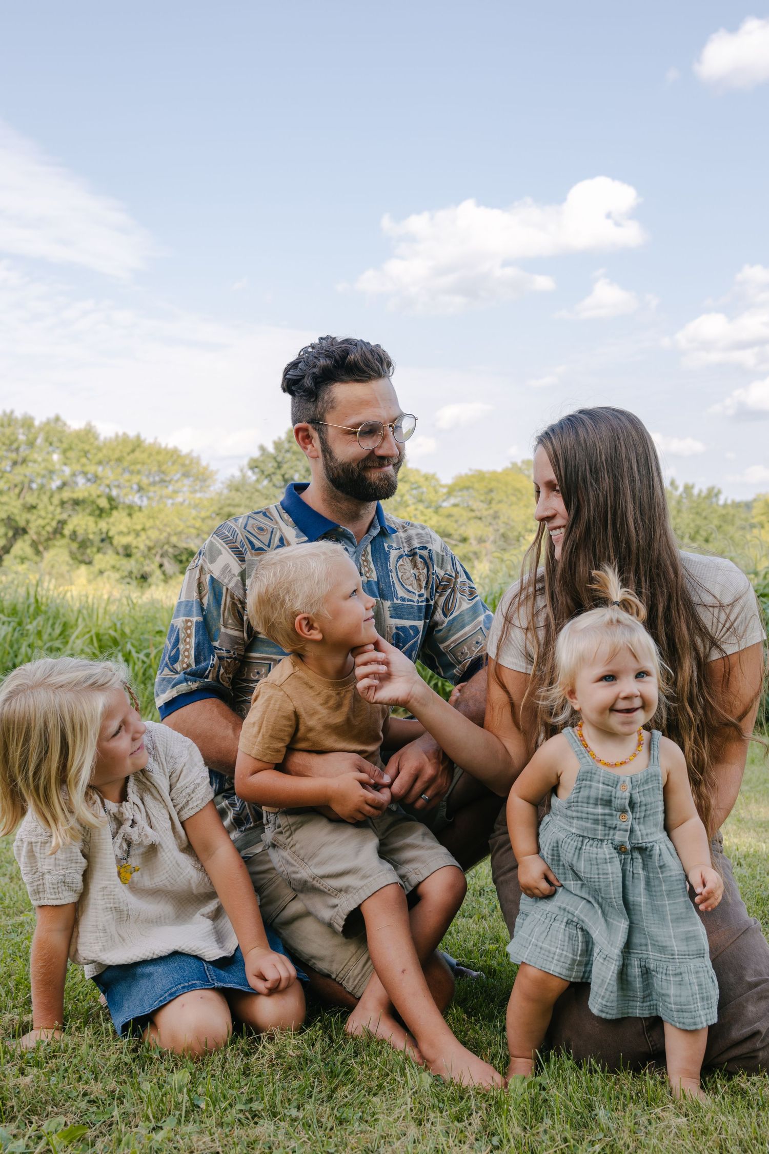 A family sits together on grass wearing coordinated neutral-toned outfits in a series of candid outdoor photos.