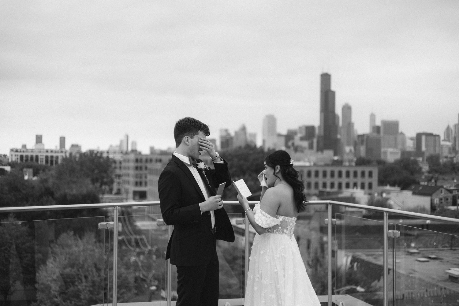 Couple exchanging vows on a rooftop with Chicago skyline backdrop in black and white wedding photo.
