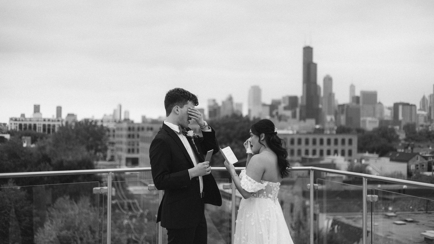 Couple exchanging vows on a rooftop with Chicago skyline backdrop in elegant black and white wedding photo.