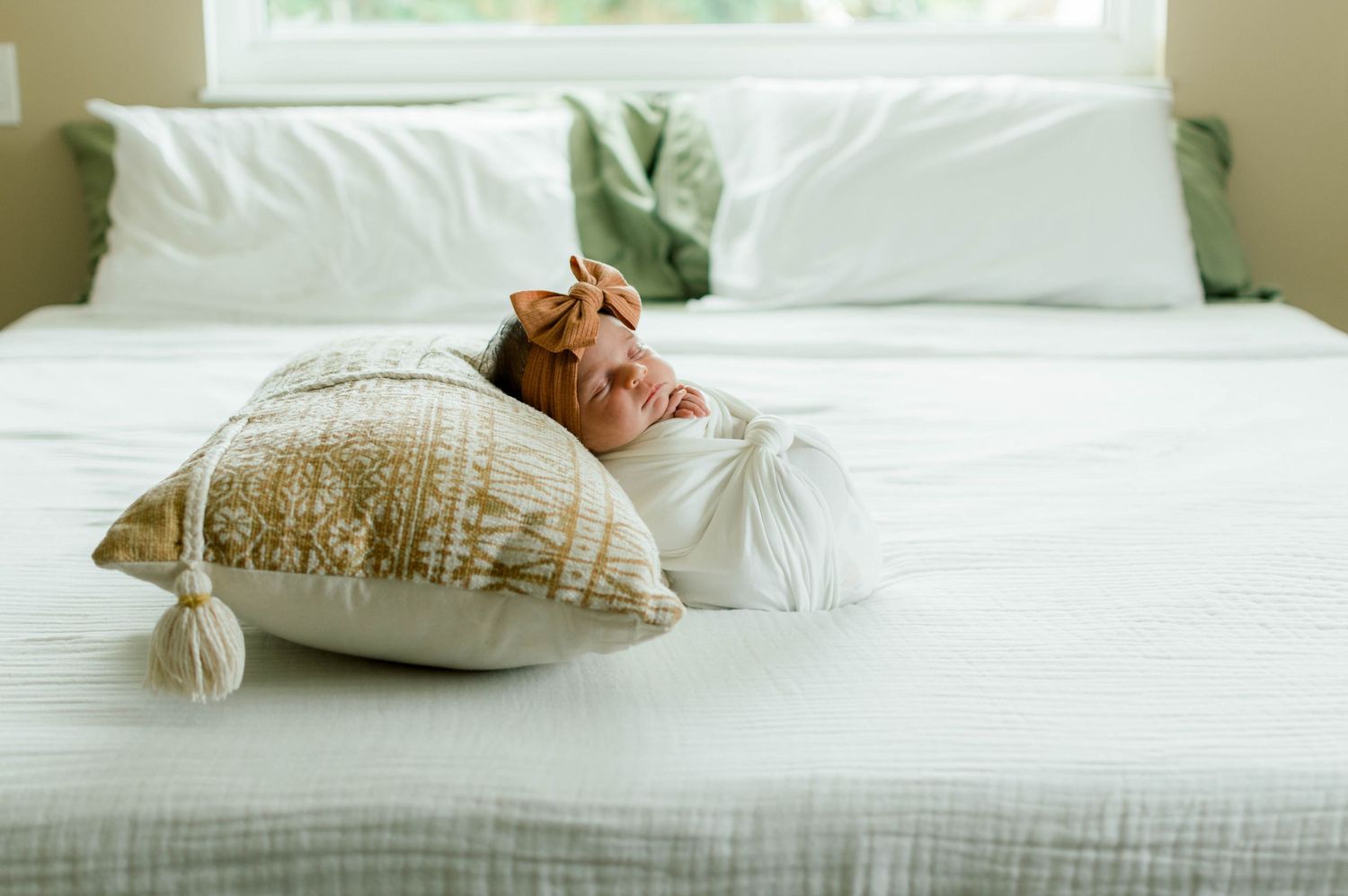 Soft natural light illuminates white bedding and pillows in tranquil bedroom setting.