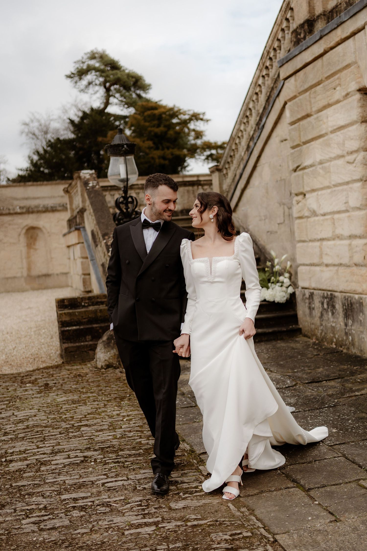 A romantic wedding photo sequence showing a couple walking and interacting along a stone wall in sepia tones.