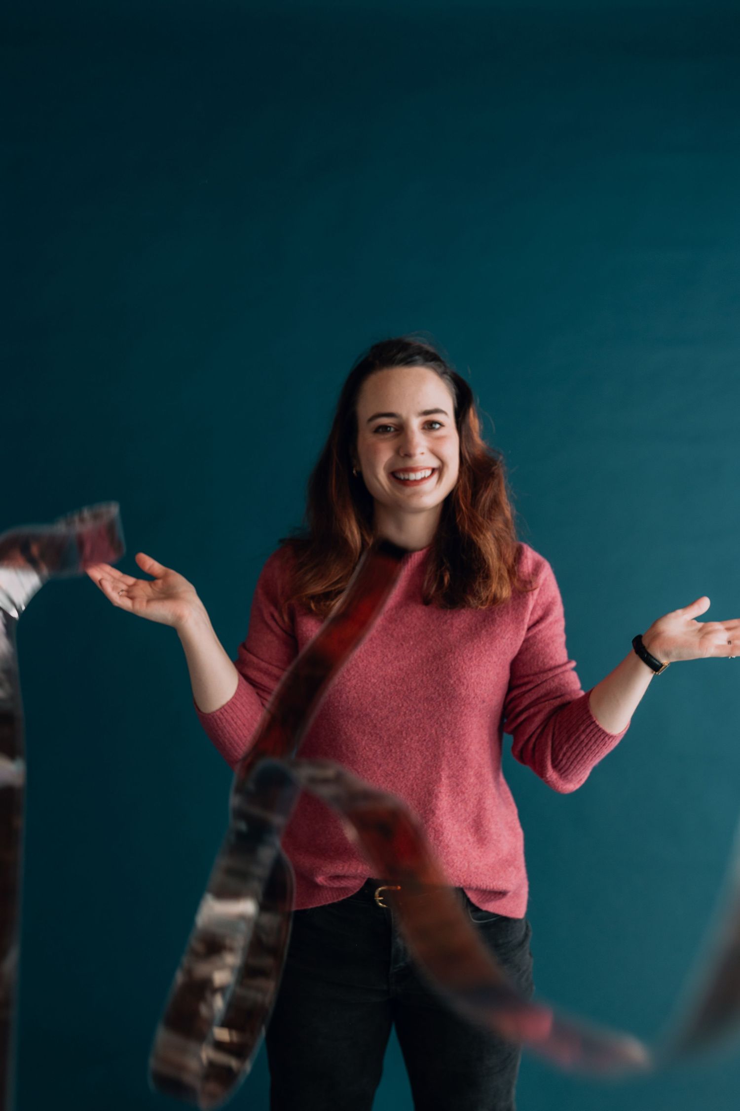 A person in a pink sweater gestures expressively against a teal background in a series of dynamic poses.