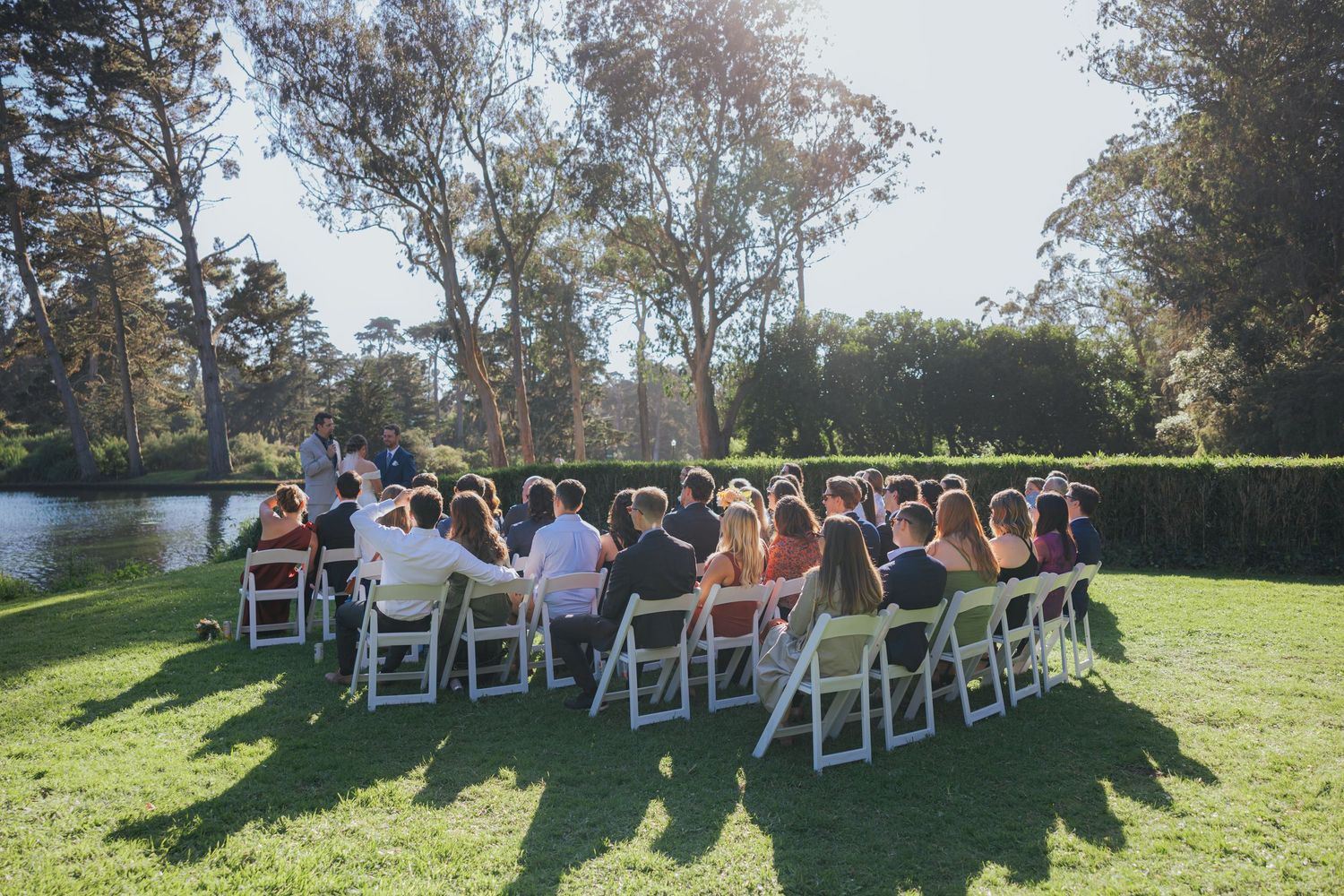White chairs set up on a grassy lawn for an outdoor wedding ceremony.