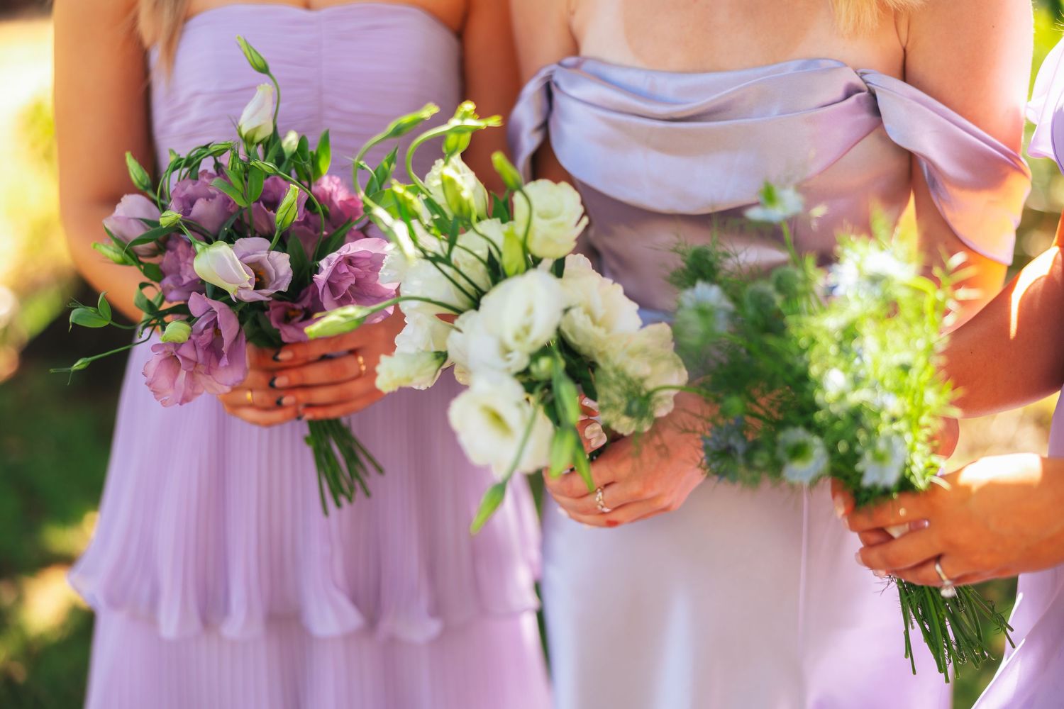 Bridesmaids in lavender dresses holding colorful floral bouquets.
