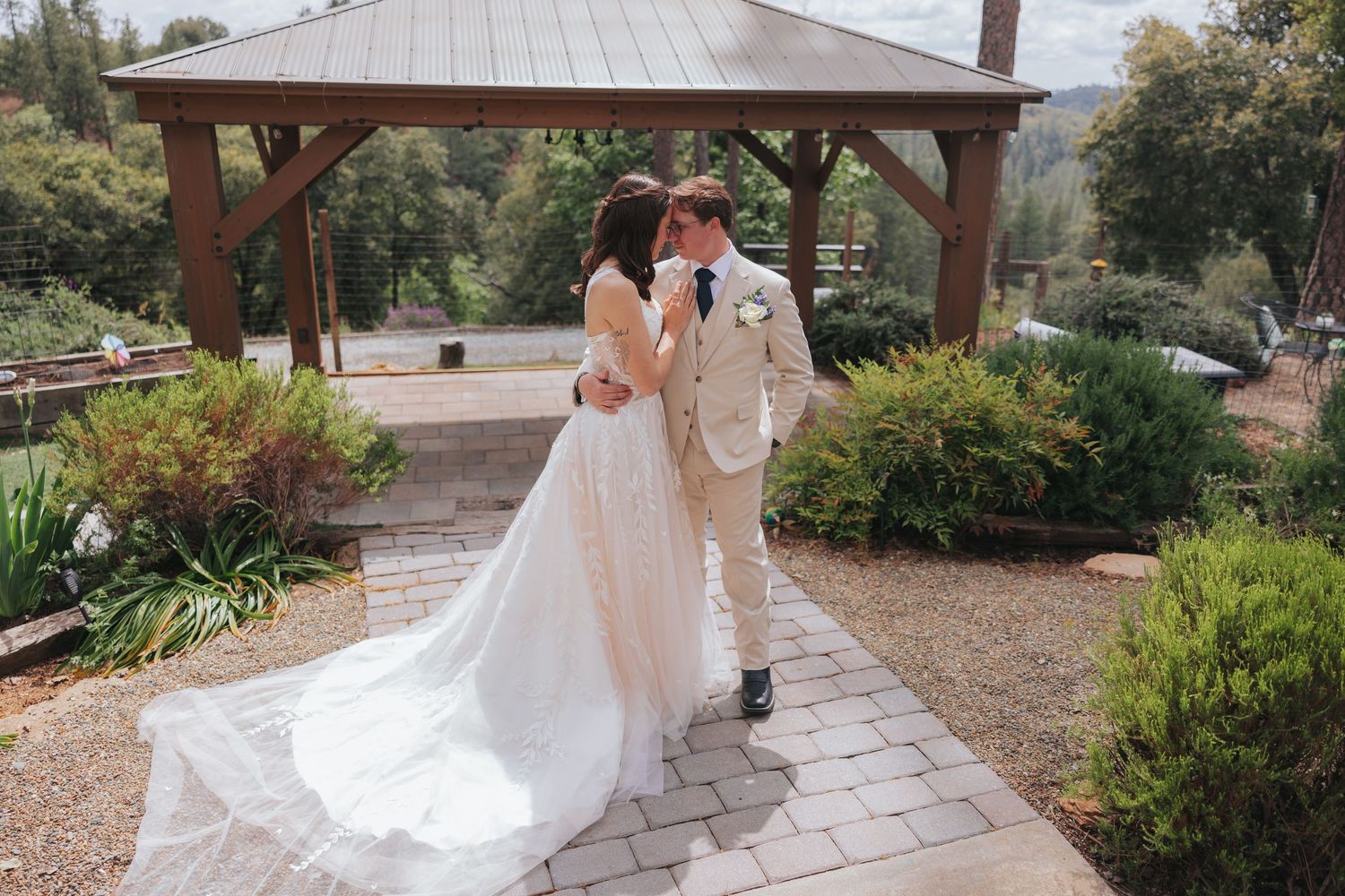 Wedding couple walking along stone pathway surrounded by landscaped garden.