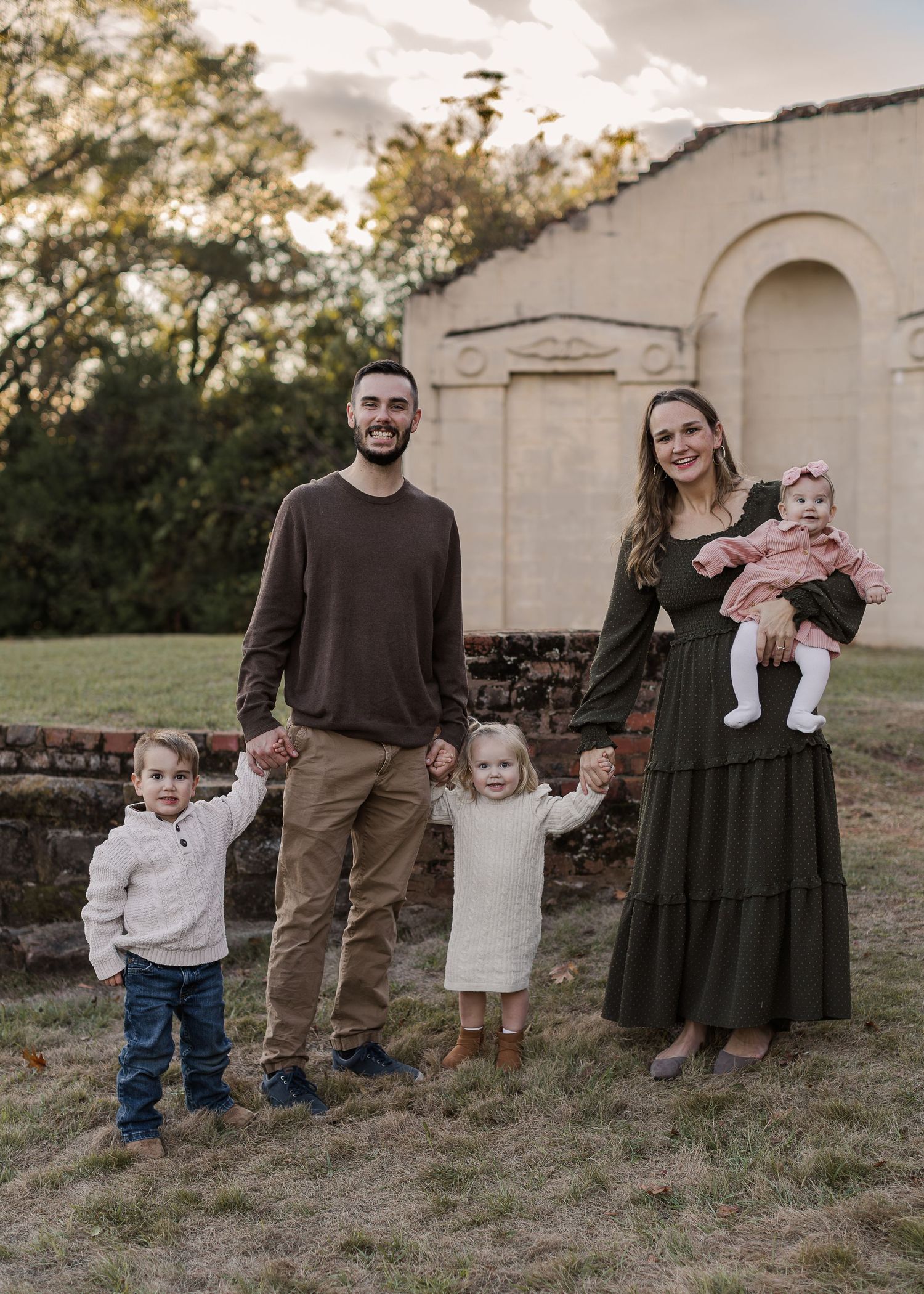 A series of outdoor family portraits showing a group in coordinating brown and olive outfits standing against a rustic wall at sunset.