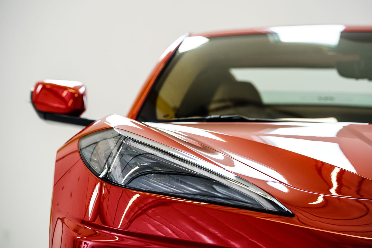 Modern red sports car headlight detail with sleek aerodynamic design.