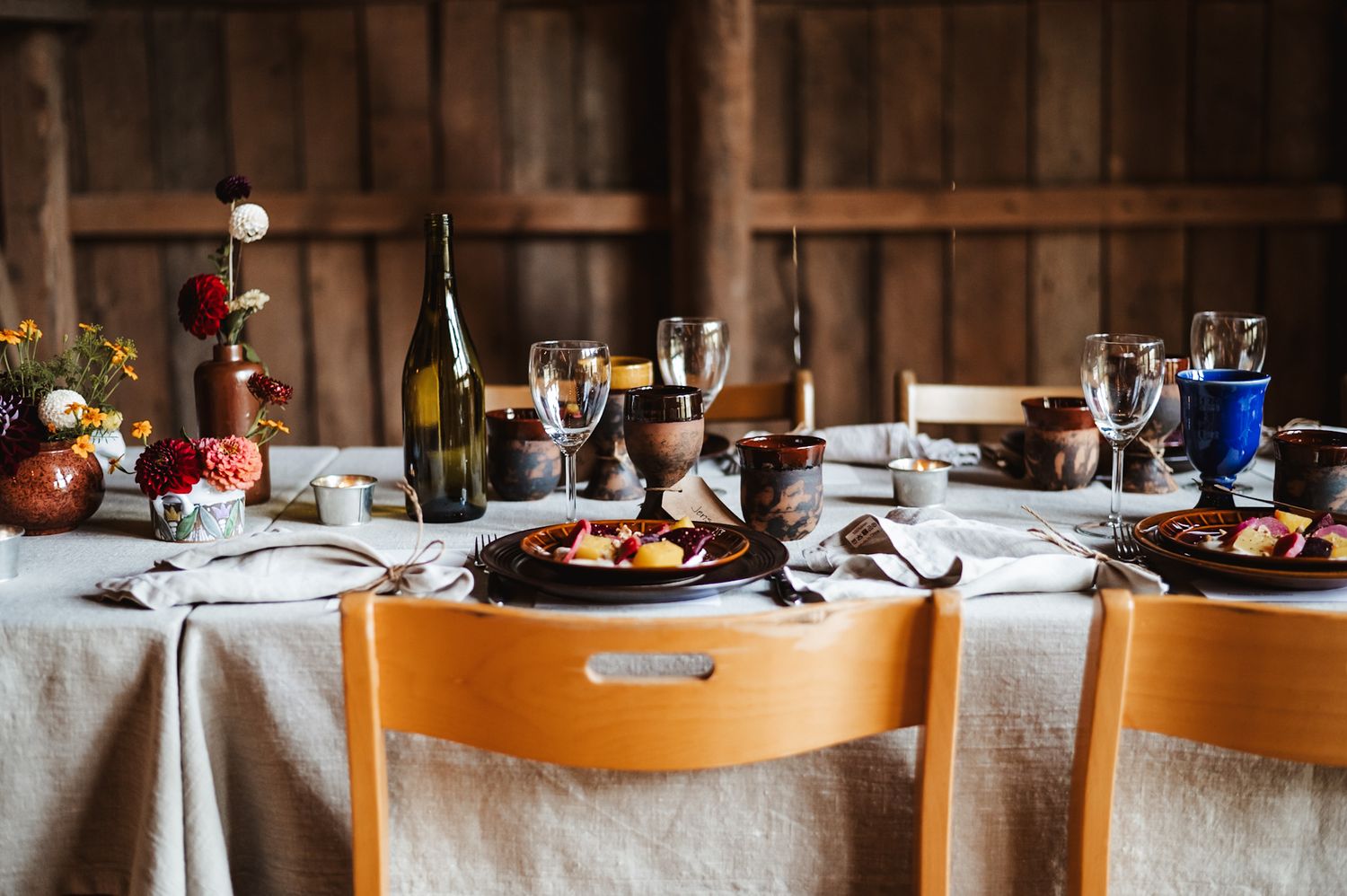 Elegant wedding reception table setting with wine bottles and rustic decor.