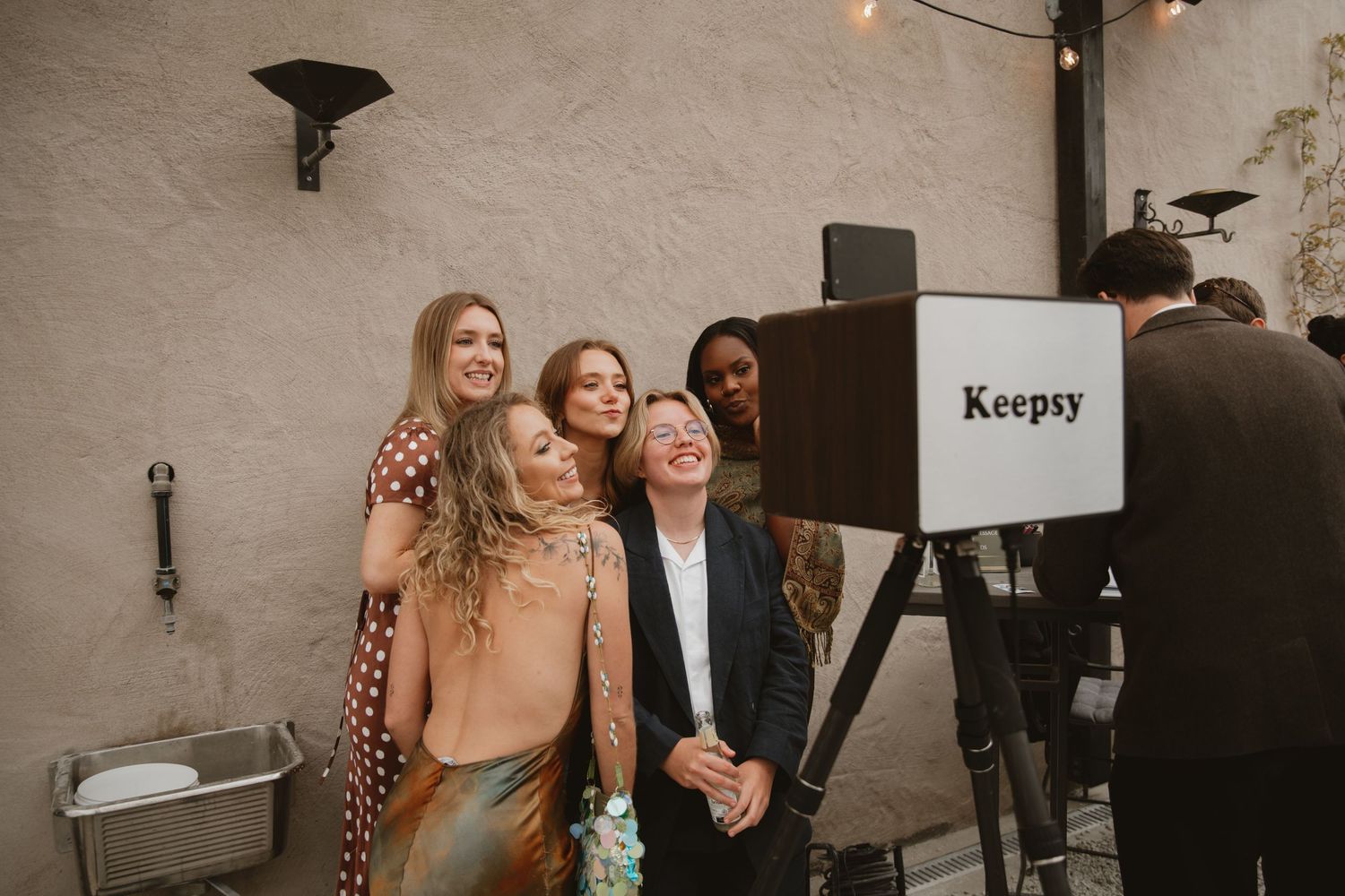 Four women pose together smiling at a Keepsy photo booth at an indoor event.