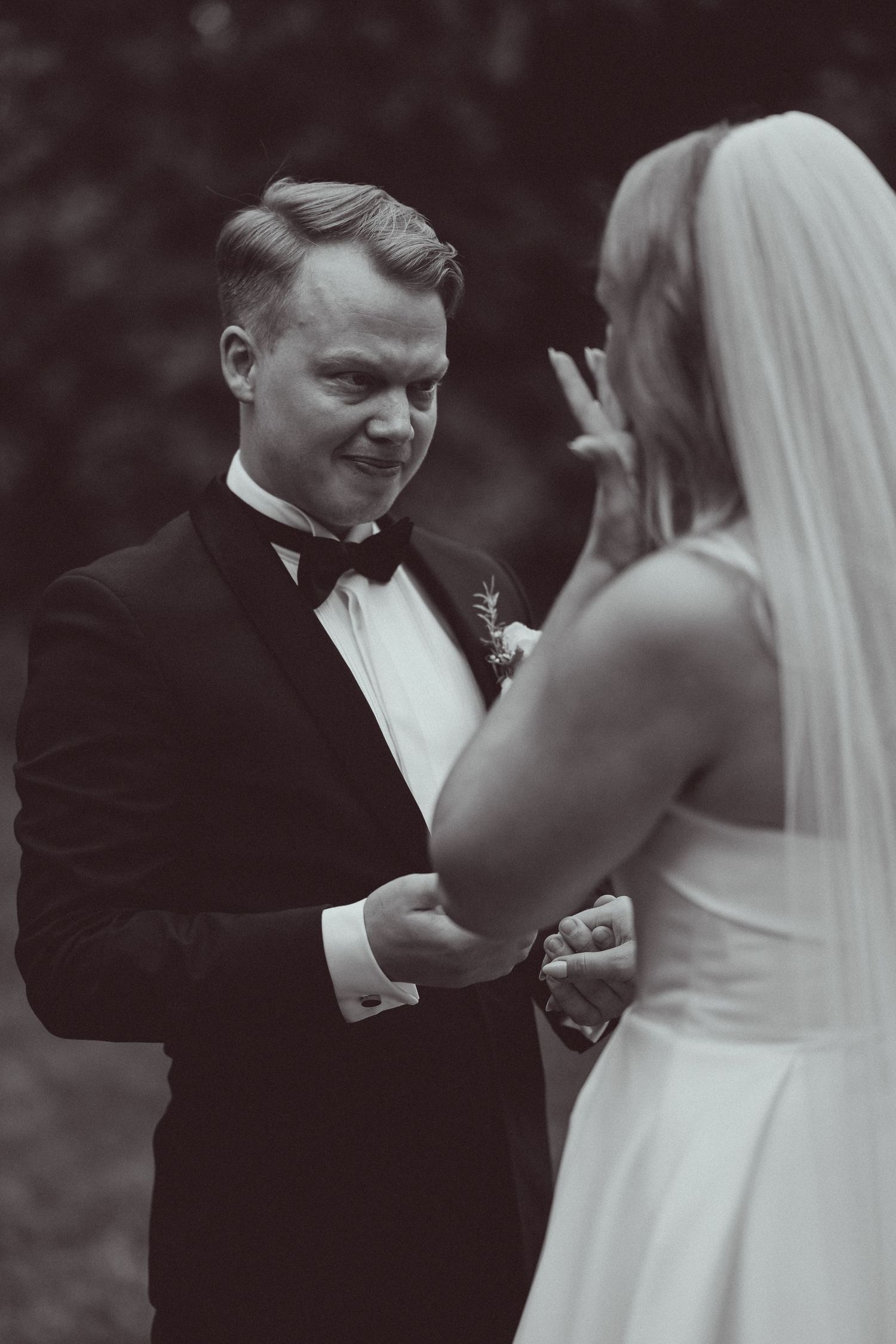 A black and white wedding photo capturing an intimate moment between newlyweds during their first look.