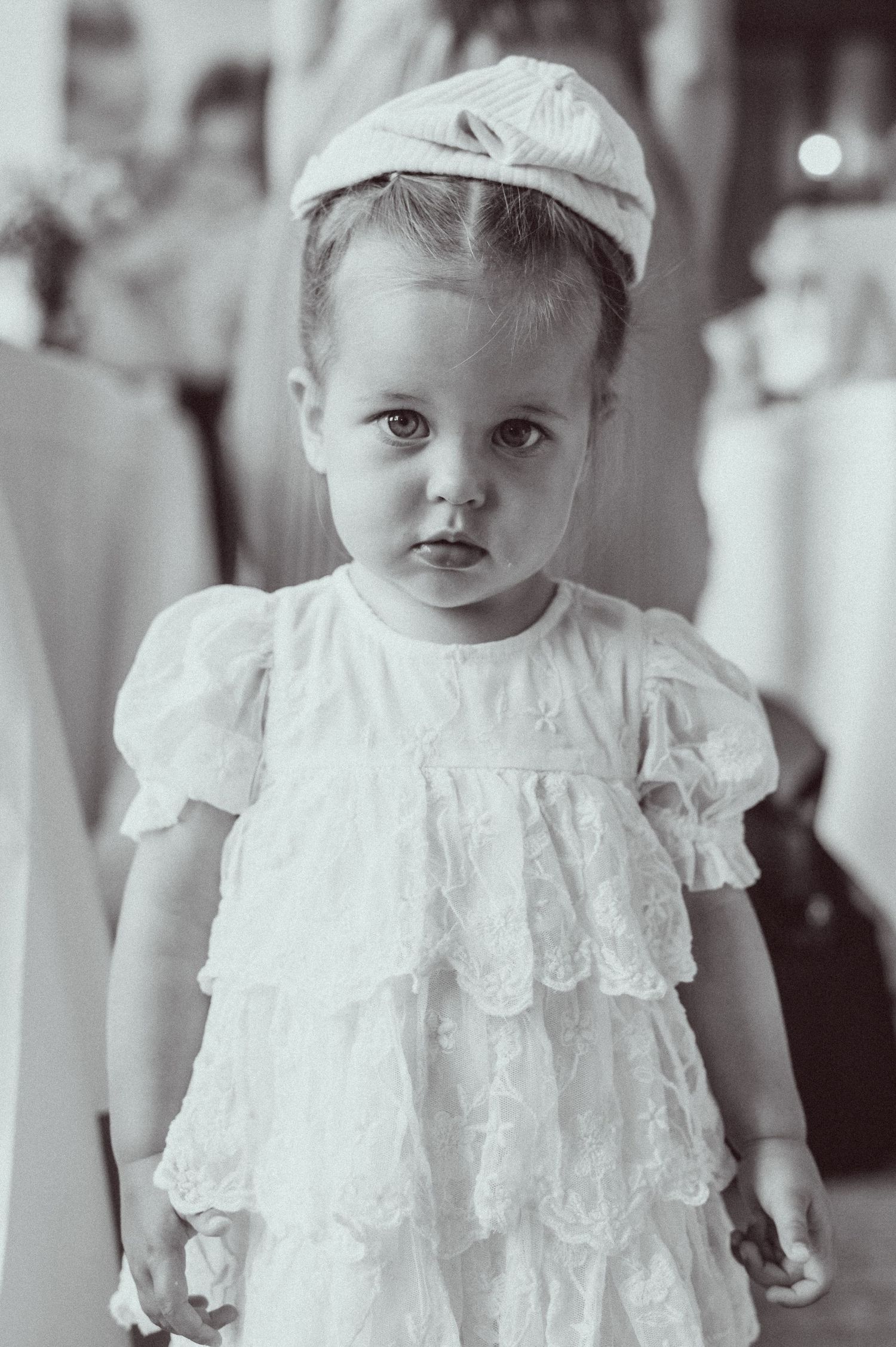 Vintage black and white portrait of a baby wearing an ornate white lace dress and cap.