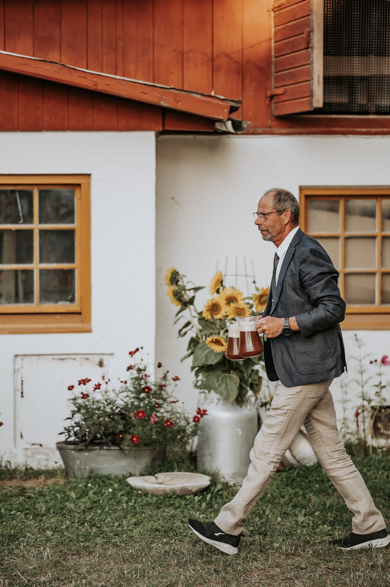 Sequence of someone carrying flowers while walking past a rustic barn wall with sunflowers.