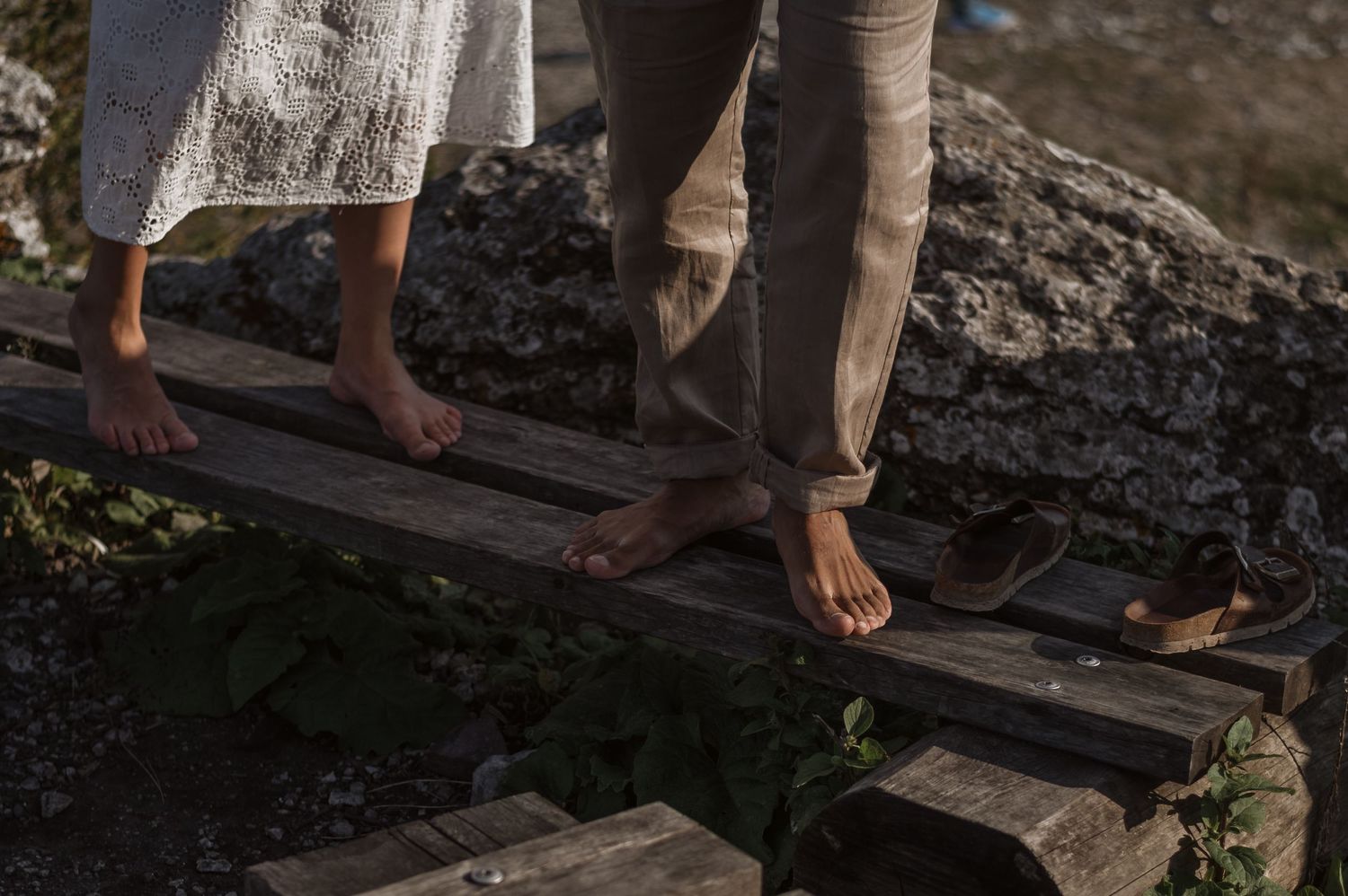 Bare feet walking on weathered wooden planks in natural lighting.