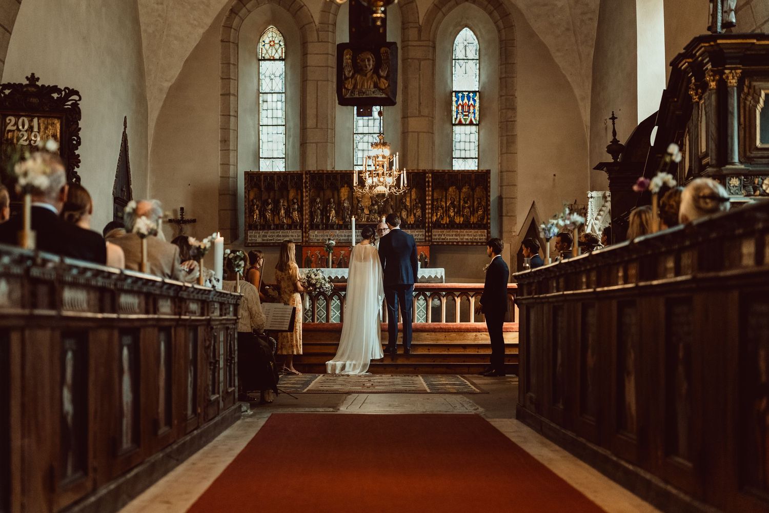 Sunlight streams through stained glass windows illuminating wooden pews in a traditional church sanctuary interior.