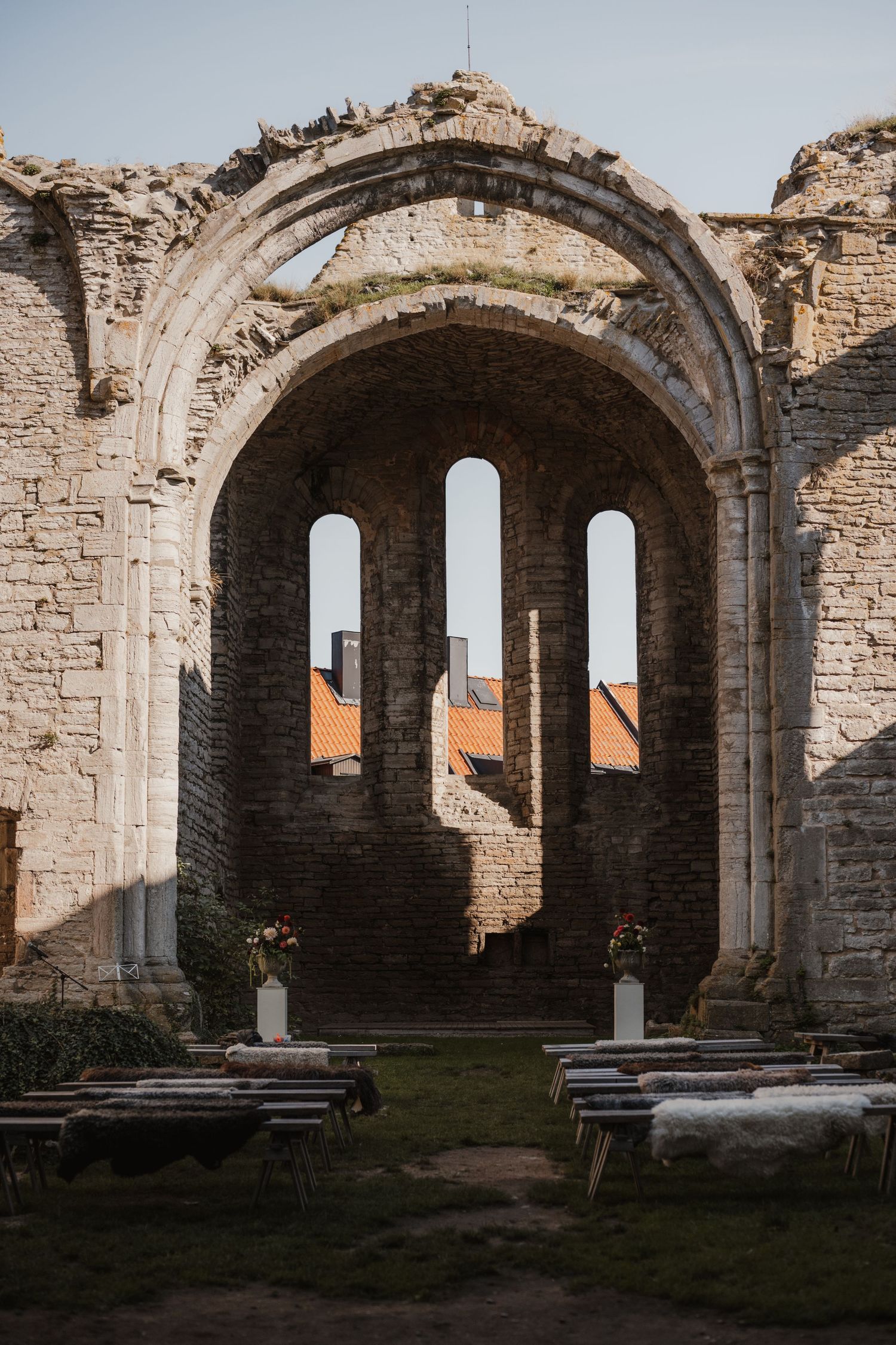 Stone archways and columns of ancient ruins with grass growing inside create a dramatic architectural panorama at sunset.
