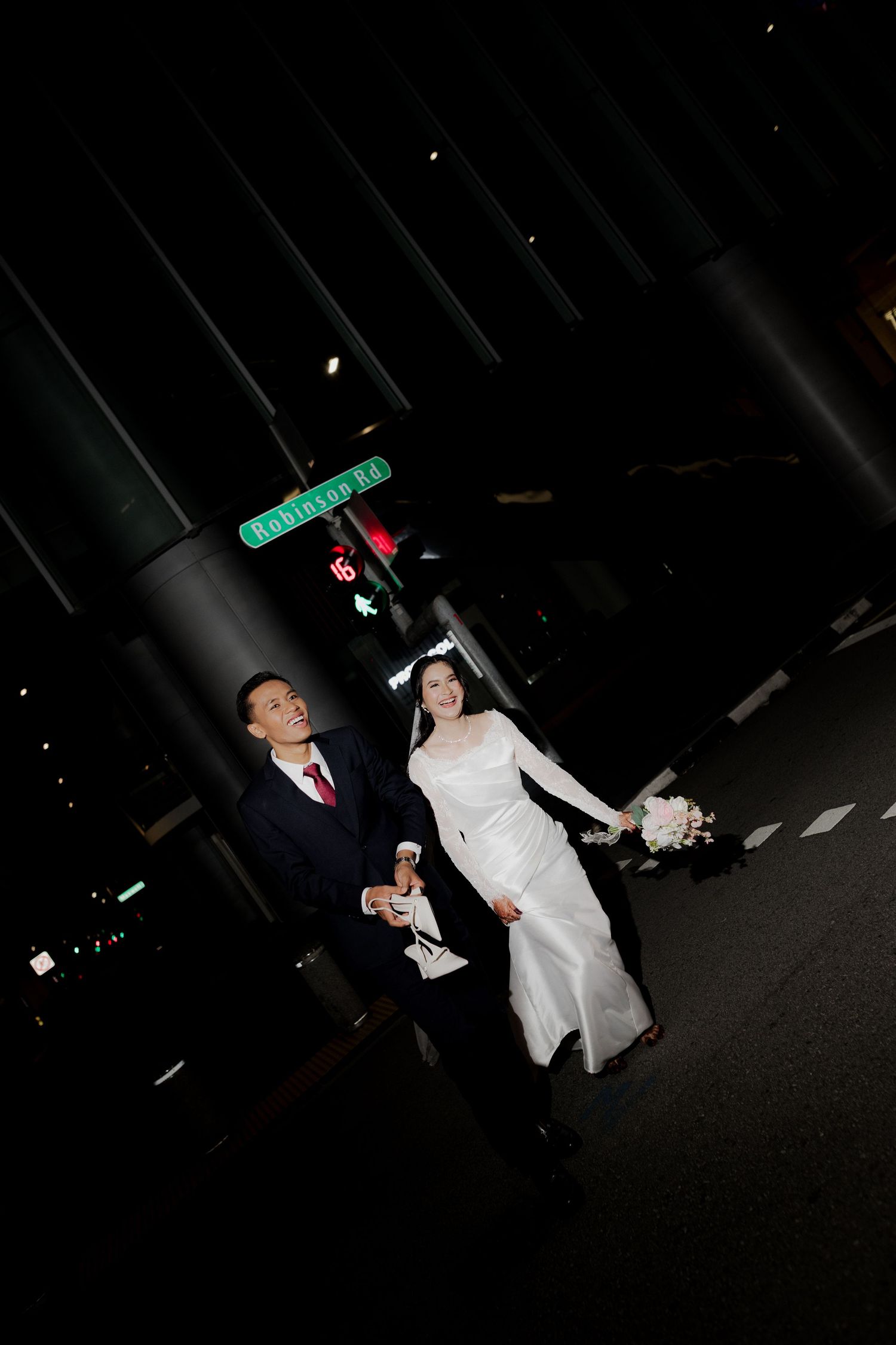 Wedding guests dancing and celebrating at a dark outdoor reception venue with glowing lights in the background.