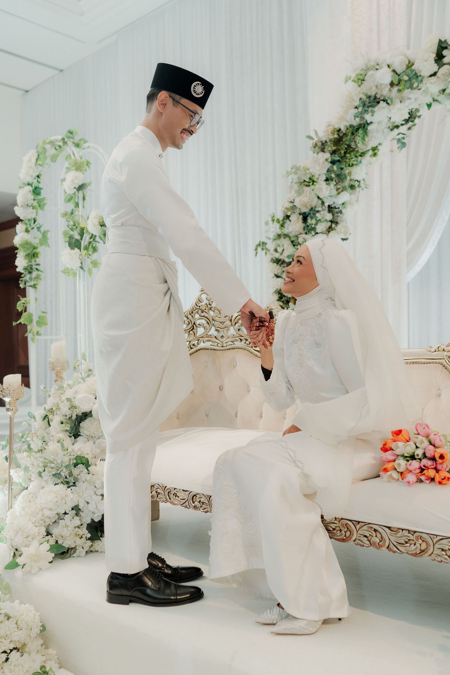A couple in traditional white wedding attire sharing a tender moment during their Islamic marriage ceremony.