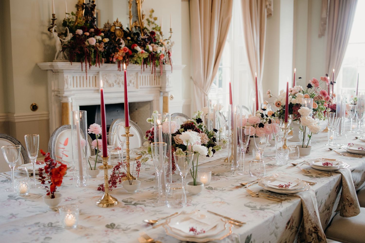 Elegant wedding reception table with pink candles, floral centerpieces, crystal glasses, and a marble fireplace backdrop.