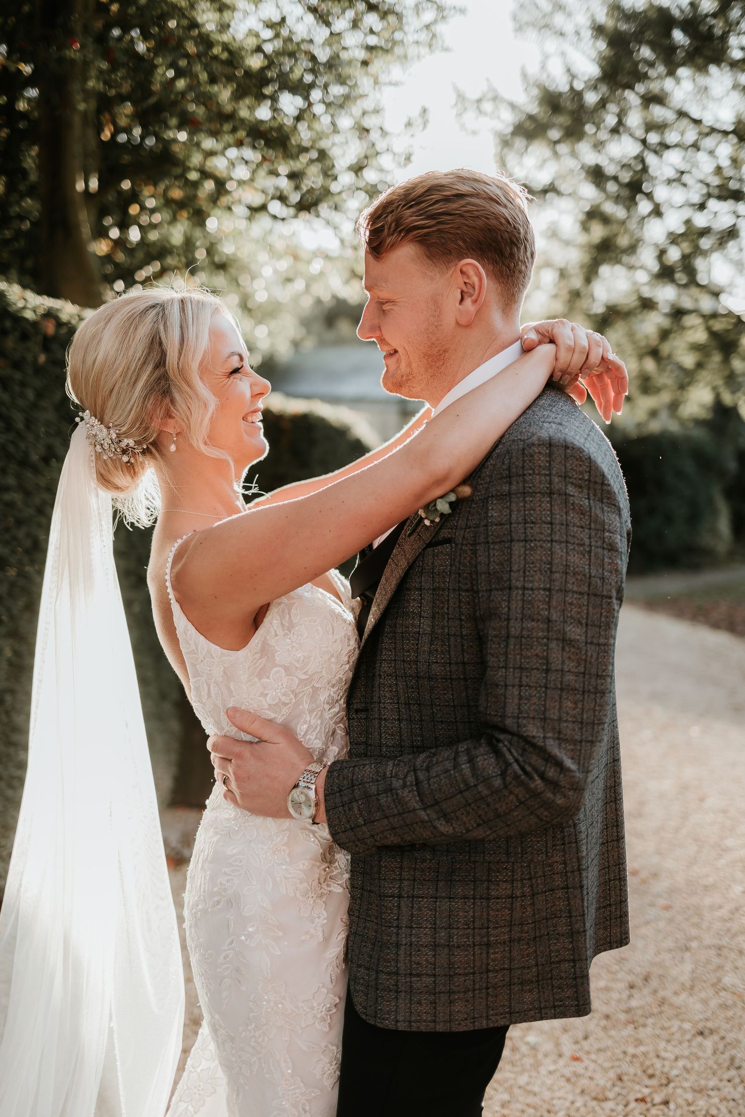 Intimate wedding portrait captured in golden sunlight on a country path.