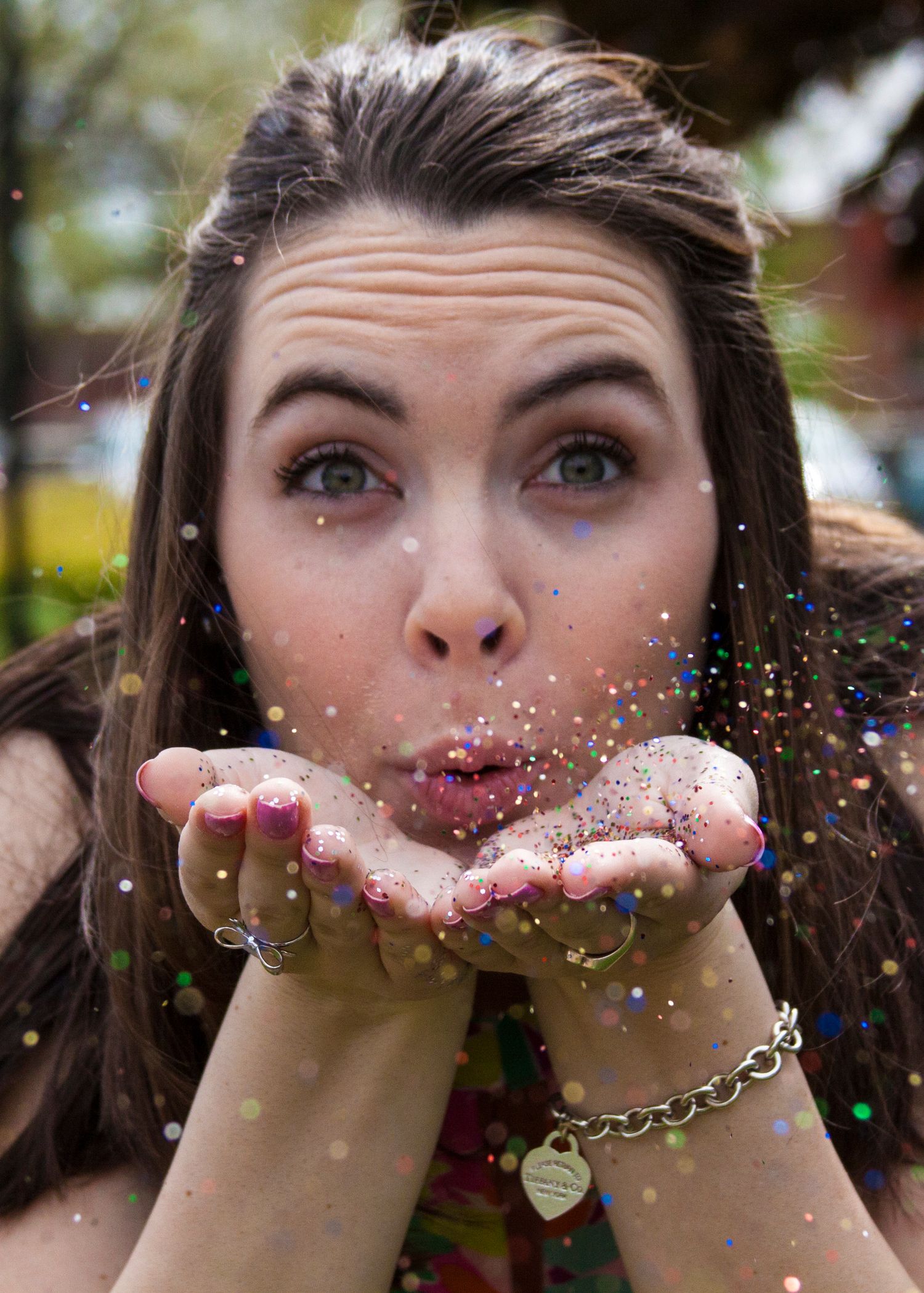 Senior portrait of a high school student blowing glitter out of her hands.