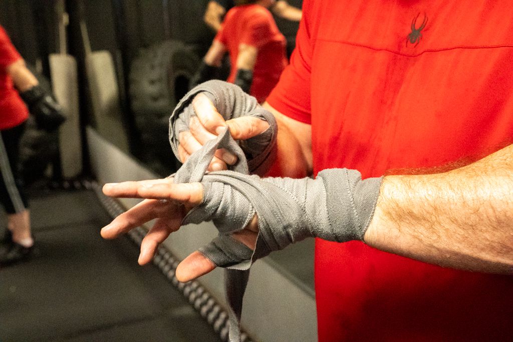 Brands photography of a boxing gym member wrapping his hands before a boxing class.