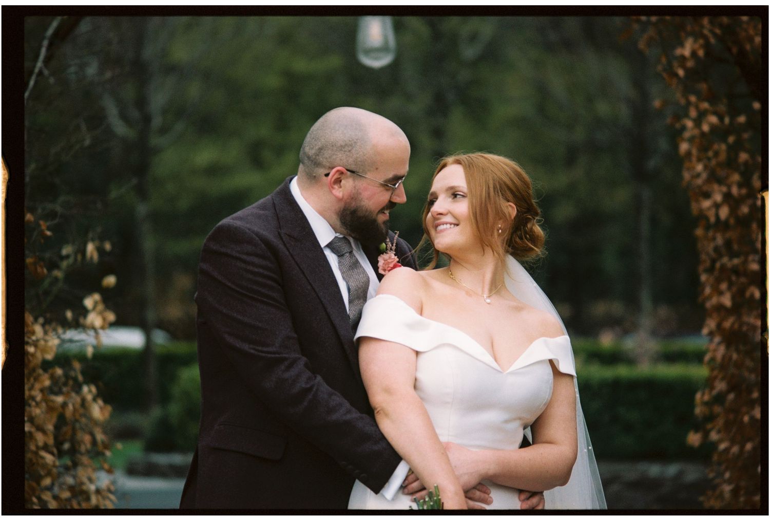 A romantic wedding couple shares an intimate moment in a lush garden setting during their outdoor celebration.