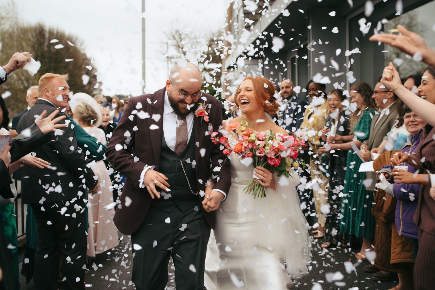 Wedding celebration with confetti being thrown at couple exiting ceremony in joyful moment.