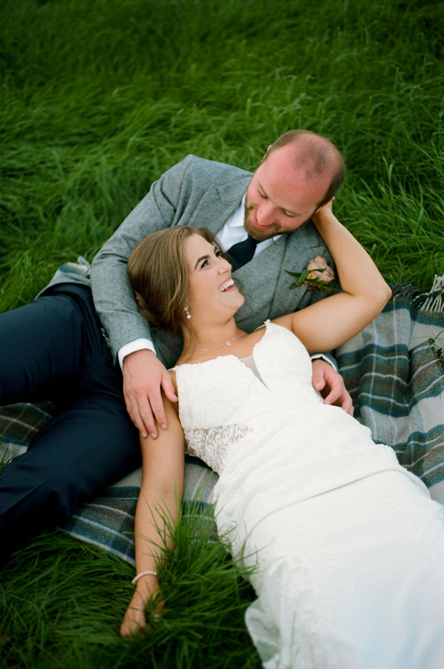 Couple lying on green grass during romantic outdoor photo session.