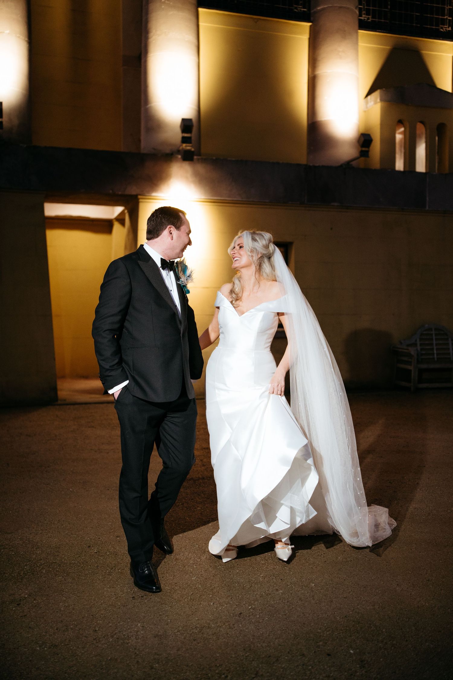 Dramatic nighttime wedding portrait with warm lighting and elegant formal attire.